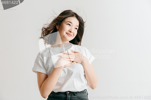 Image of Happy asian woman standing and smiling against gray background.