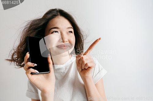 Image of Portrait of a confident casual asian girl showing blank screen of mobile phone