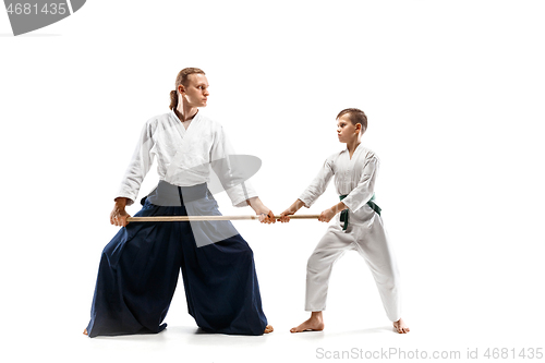 Image of Man and teen boy fighting with wooden swords at Aikido training in martial arts school