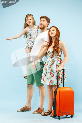 Image of Happy parent with daughter and suitcase at studio isolated on blue background