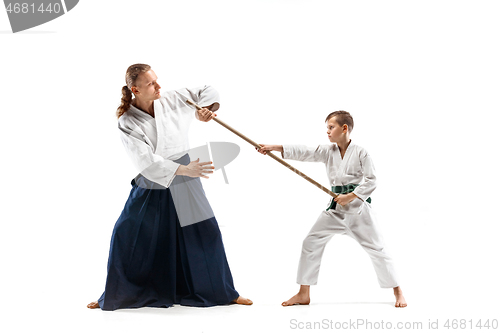 Image of Man and teen boy fighting with wooden swords at Aikido training in martial arts school