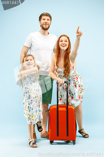 Image of Happy parent with daughter and suitcase at studio isolated on blue background