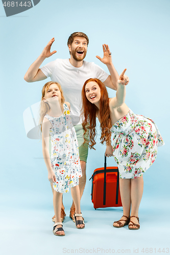 Image of Happy parent with daughter and suitcase at studio isolated on blue background