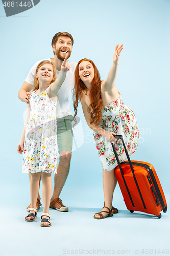 Image of Happy parent with daughter and suitcase at studio isolated on blue background