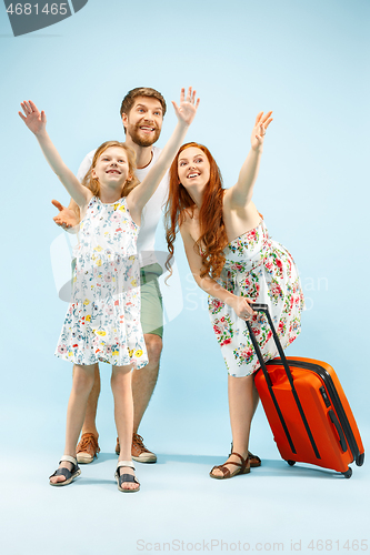 Image of Happy parent with daughter and suitcase at studio isolated on blue background