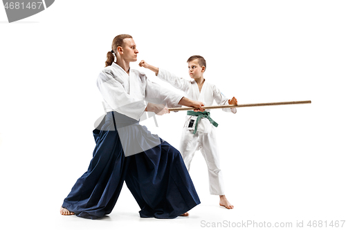 Image of Man and teen boy fighting with wooden swords at Aikido training in martial arts school