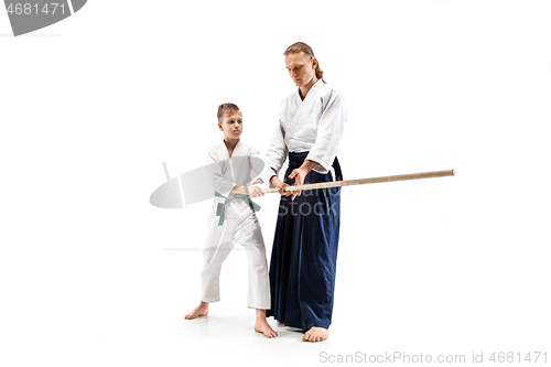 Image of Man and teen boy fighting with wooden swords at Aikido training in martial arts school