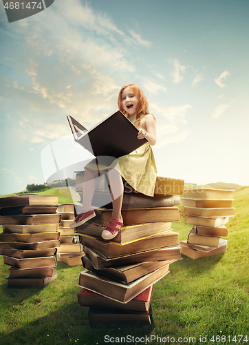 Image of Little Girl sitting on the tower made of big books