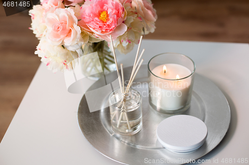 Image of aroma reed diffuser, candle and flowers on table