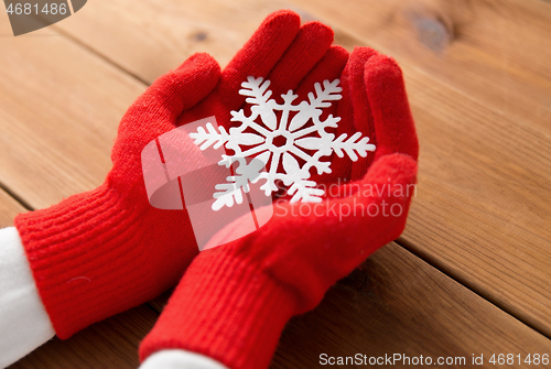 Image of hands in red woollen gloves holding big snowflake