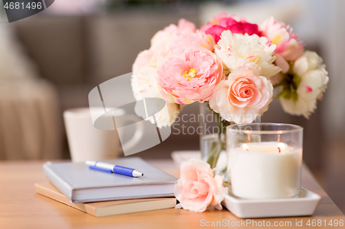 Image of burning candle and flower bunch on wooden table