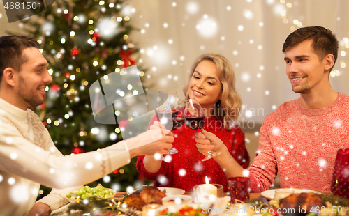 Image of happy friends drinking red wine at christmas party
