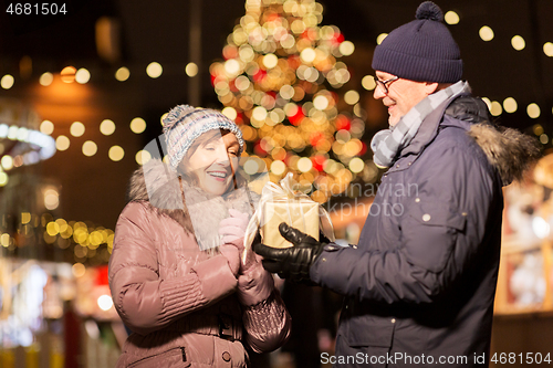 Image of happy senior couple with gift at christmas market