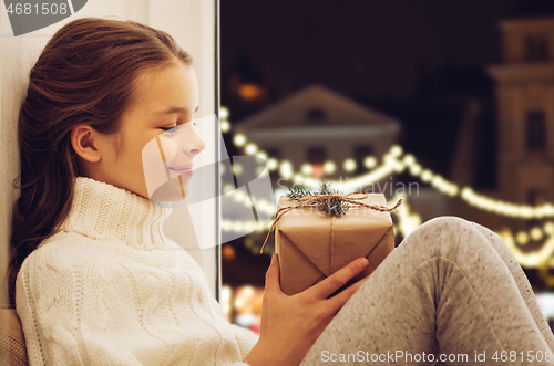 Image of girl with christmas gift sitting at window