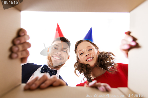 Image of couple in party hats opening birthday gift box