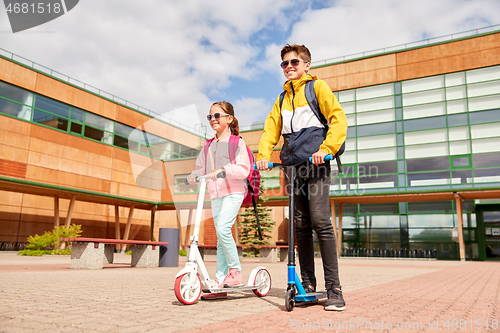 Image of happy school children with backpacks and scooters