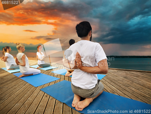 Image of group of people making yoga exercises outdoors