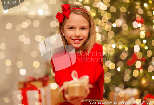 Image of smiling girl with christmas gift at home