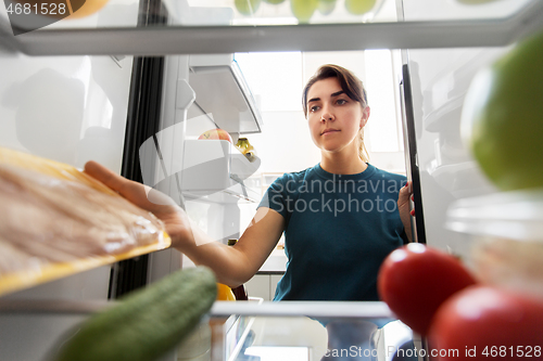 Image of woman taking food from fridge at home