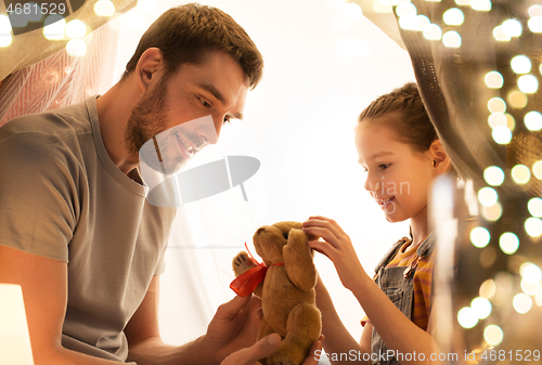 Image of happy family playing with toy in kids tent at home