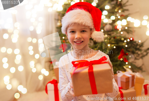 Image of smiling girl in santa hat with christmas gift