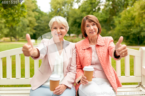 Image of senior women with coffee showing thumbs up at park
