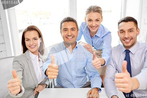 Image of happy business team showing thumbs up at office