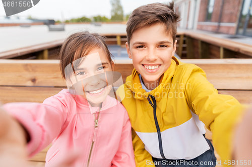 Image of children sitting on street bench and taking selfie