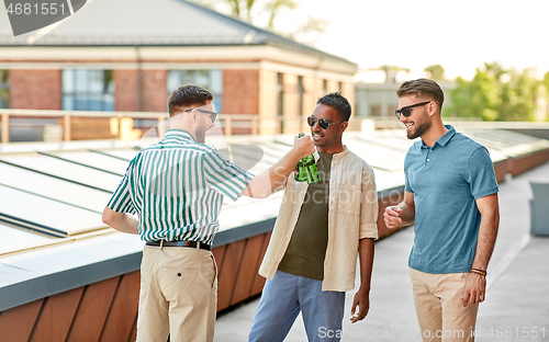Image of happy male friends drinking beer at rooftop party