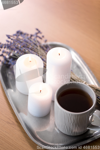 Image of candles, tea in mug and lavender flowers on table