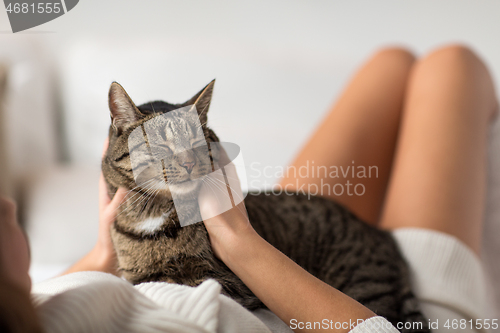 Image of happy young woman with cat lying in bed at home