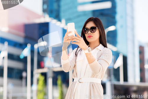 Image of asian woman taking selfie by smartphone in city