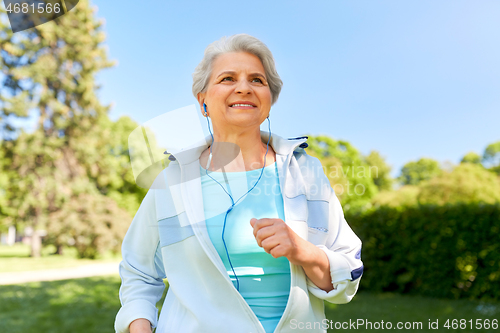 Image of senior woman with earphones running in summer park