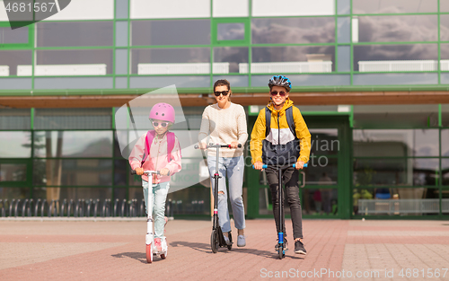 Image of happy school children with mother riding scooters