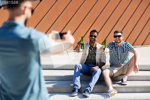 Image of man photographing friends drinking beer on street