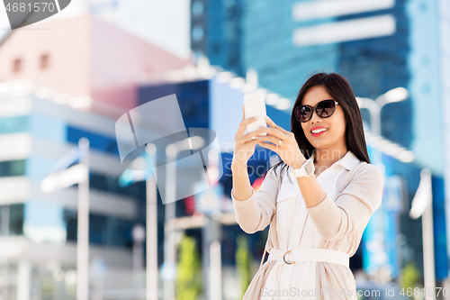 Image of asian woman taking selfie by smartphone in city