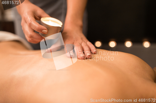 Image of back massage with hot oil candle at spa