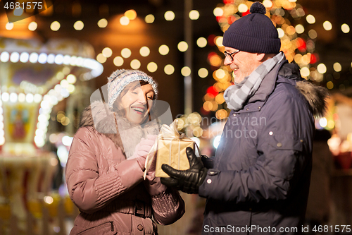 Image of happy senior couple with gift at christmas market