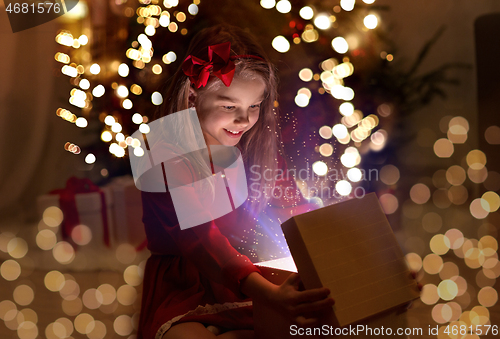 Image of smiling girl opening christmas gift at night