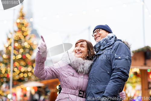 Image of happy senior couple hugging at christmas market