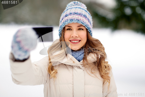 Image of woman taking selfie by smartphone in winter