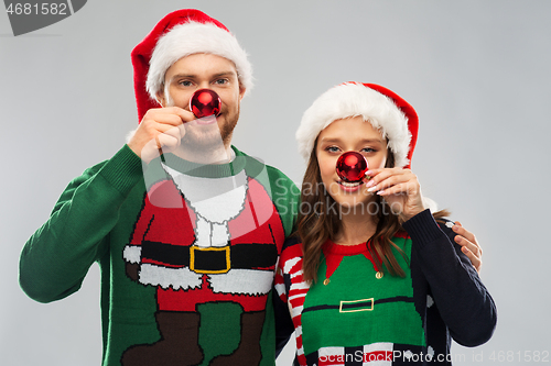 Image of happy couple in christmas sweaters and santa hats