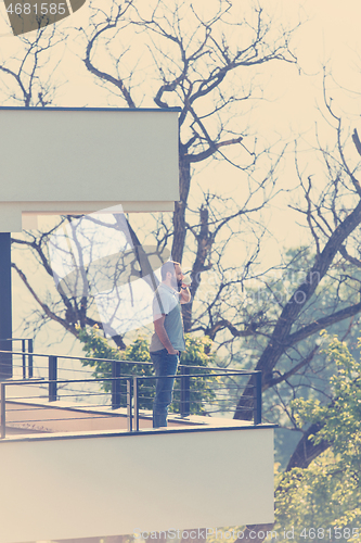 Image of man drinking morning coffee on balcony