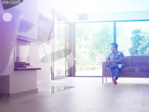 Image of Man using laptop in living room