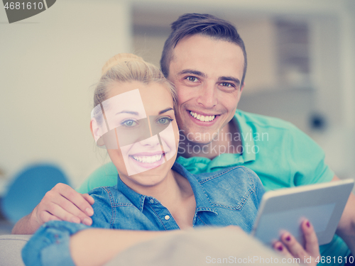 Image of couple relaxing at  home with tablet computers