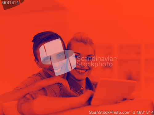 Image of couple relaxing at  home with tablet computers