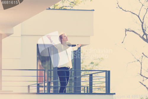 Image of woman stretching her arms on balcony