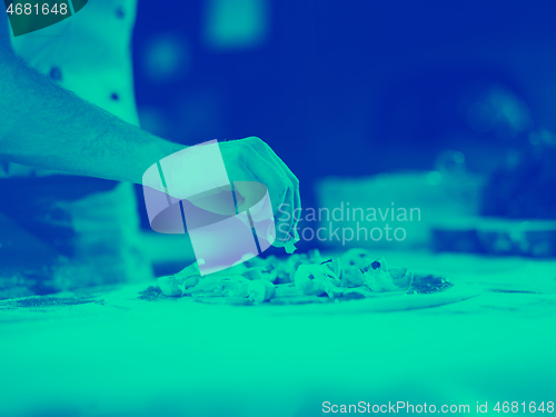 Image of chef putting fresh mushrooms on pizza dough