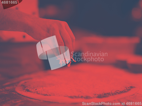 Image of chef sprinkling cheese over fresh pizza dough