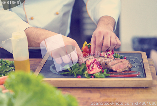 Image of closeup of Chef hands serving beef steak